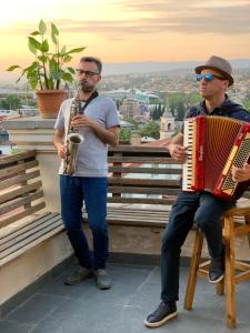 dwóch mężczyzn siedzących na ławce z akordeonem w obiekcie Betlemi Old Town Hotel w mieście Tbilisi City