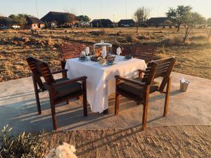 uma mesa com uma toalha de mesa branca e duas cadeiras em Morakane Safari Lodge em Vryburg