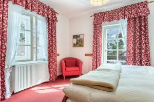 a bedroom with red curtains and a bed and a red chair at Voglsang - Haus Annamirl in Bayrischzell