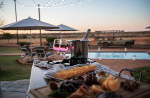 a table with a plate of food and a glass of wine at Morakane Safari Lodge in Vryburg
