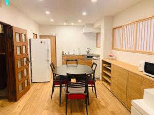 uma cozinha com uma mesa e cadeiras e um frigorífico em Yokohama HY House em Yokohama