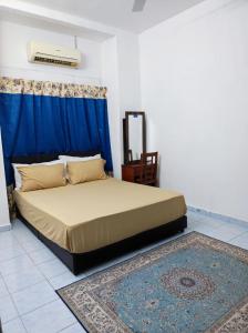 a bedroom with a bed with a blue curtain and a rug at D'Hiquapis Homestay in Seri Manjung