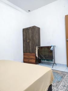 a bedroom with a bed and a dresser and a tv at D'Hiquapis Homestay in Seri Manjung