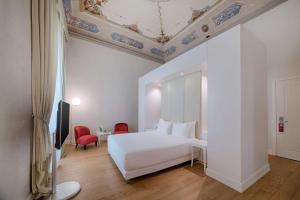 a bedroom with a white bed and a ceiling at NH Collection Firenze Porta Rossa in Florence