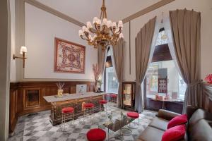 a living room with a chandelier and a table and chairs at NH Collection Firenze Porta Rossa in Florence