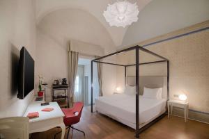 a bedroom with a white bed and a desk with a chair at NH Collection Firenze Porta Rossa in Florence