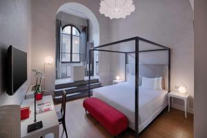 een slaapkamer met een bed en een bureau met een televisie bij NH Collection Firenze Porta Rossa in Florence