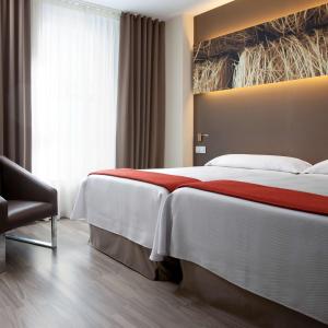 a hotel room with two beds and a television at NH Barcelona Diagonal Center in Barcelona