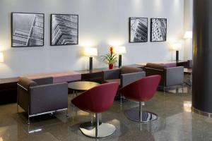 a waiting room with chairs and tables and pictures on the wall at NH Barcelona Diagonal Center in Barcelona