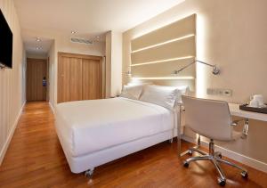 a bedroom with a white bed and a desk and a chair at NH Barcelona Les Corts in Barcelona