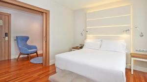 a bedroom with a bed and a blue chair at NH Barcelona Les Corts in Barcelona
