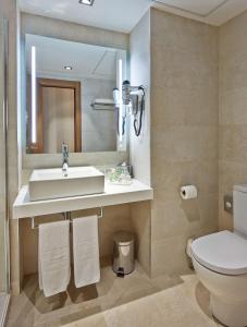 a bathroom with a sink and a toilet and a mirror at NH Barcelona Les Corts in Barcelona