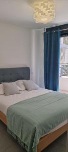 een slaapkamer met een groot bed en een blauw gordijn bij Appartement de 2 chambres avec vue sur la mer et wifi a Porto Vecchio a 5 km de la plage in Porto-Vecchio