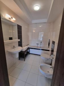 a bathroom with two sinks and a tub and two toilets at Apartament Perła A20 nad jeziorem Pluszne in Olsztynek