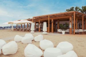 a building on the beach with white chairs and umbrellas at Pizzomunno Vieste Palace Hotel in Vieste