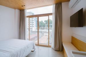 a bedroom with a bed and a large window at Cityhouse - Ariosa in Ho Chi Minh City