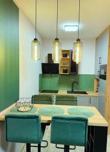 a kitchen with a table and some green chairs at APARTAMENT ELEGANCE GREEN w Let's Sea in Gąski