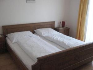 a bedroom with a bed with white sheets and a window at 2 Sterne Pension Gasthof ohne Internet in Steinbach am Attersee