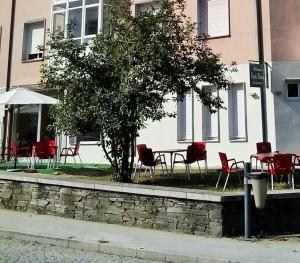 stół i krzesła oraz drzewo przed budynkiem w obiekcie Pensión-Albergue Puente Ribeira w mieście Sarria