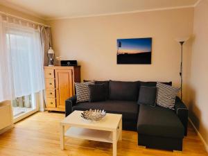 a living room with a black couch and a table at Strandapartment in Westerland für 2-4 Personen in Westerland