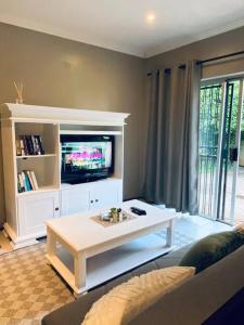 a living room with a tv and a white coffee table at The Cottage at 152 in Centurion +5 photos