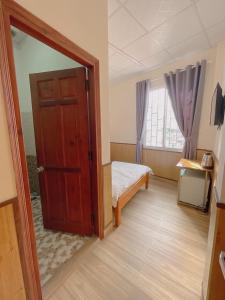 1 dormitorio con puerta, cama y ventana en CATTLEYA HOTEL en Da Lat