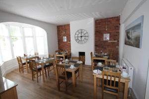 a dining room with tables and chairs and a brick wall at Cranmore Bed & Breakfast in Torquay