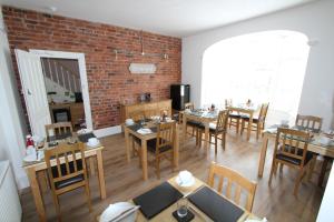 a dining room with tables and chairs and a brick wall at Cranmore Bed & Breakfast in Torquay