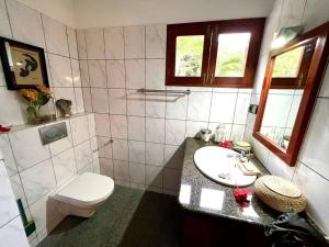 a white bathroom with a toilet and a sink at Hilltop South - Villa Bougainville in Takamaka