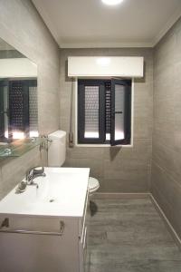 een badkamer met een wastafel, een toilet en een raam bij Casa Horizonte in Nazaré