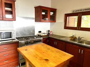 a kitchen with a stove and a wooden counter top at Hilltop South - Villa Bougainville in Takamaka