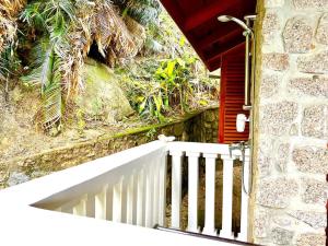 a white railing next to a building with a red door at Hilltop South - Villa Bougainville in Takamaka