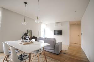 uma sala de jantar branca com uma mesa e cadeiras brancas em Aljube Residences II - Apartamento novo centro PDL em Ponta Delgada