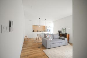 uma sala de estar com um sofá e uma cozinha em Aljube Residences II - Apartamento novo centro PDL em Ponta Delgada