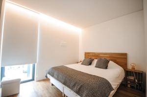 um quarto com uma cama e uma grande janela em Aljube Residences II - Apartamento novo centro PDL em Ponta Delgada