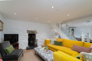 a living room with a yellow couch and a fireplace at Shrimp Cottage in St Ives