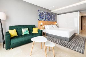 um quarto de hotel com uma cama e um sofá verde em Mid Town Hotel Casablanca em Casablanca