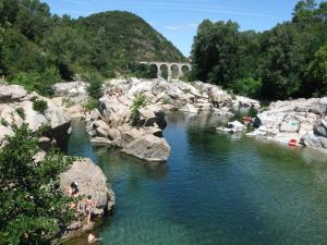 a river with rocks and a bridge in the background at LE GÎTE LA BLAQUIÉRE in Cendras