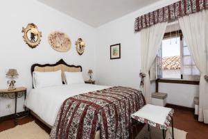 Un dormitorio con una gran cama blanca y una ventana. en Casa de S. Thiago do Castelo, en Óbidos