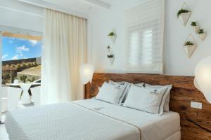 a bedroom with a bed with white sheets and a window at Elements Sifnos Boutique in Faros