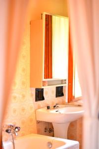 uma casa de banho com um lavatório, um espelho e uma banheira em B&B Claudia em Romeno
