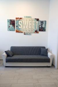 un sofá en una habitación con tres pinturas en la pared en Home Sweet Home en Civitavecchia