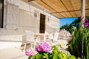 un patio con sedie bianche, tavoli e fiori di Guest House Rooms Rose a Molunat