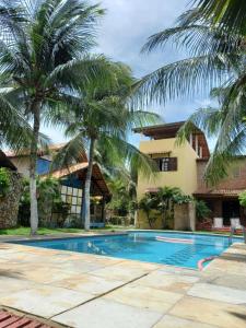 a villa with a swimming pool and palm trees at Pousada Refúgio do Manatí in Canoa Quebrada