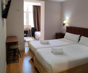 a hotel room with two beds and a window at Hotel Cuéntame La Puebla in Burgos