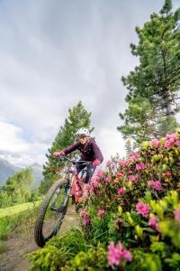 a person riding a bike on a trail with flowers at 4 Sterne Superior Mühle Resort 1900 - Adults only in Obergurgl