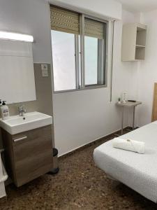 a bathroom with a sink and a bed and a window at Hostal Milmarcos in Zaragoza