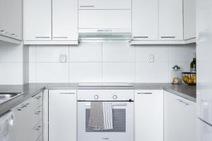 een witte keuken met witte kasten en een oven bij Arctic Aurora City Suite in Rovaniemi