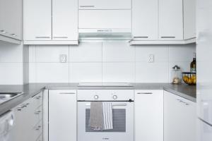 een witte keuken met witte kasten en een oven bij Arctic Aurora City Suite in Rovaniemi +4 foto's