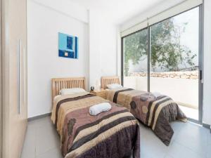 two beds in a room with a large window at Villa Calypso in Polis Chrysochous